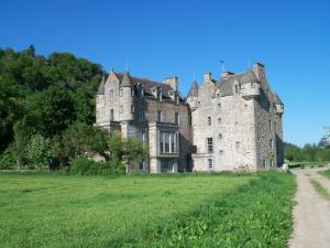 an old castle in a field with a dirt road at The Keepers in Aberfeldy