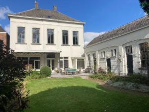 een groot wit huis met een groene bank in de tuin bij Bed & Breakfast By Genck in Oudenbosch