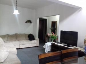 sala de estar con sofá y TV de pantalla plana en Pousada Bom Jesus, en Ponta Grossa