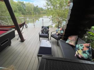 a deck with couches and chairs on a boat at Woodpecker Log Cabin with hot tub, pizza oven bbq entertainment area, lakeside with private fishing peg situated at Tattershall Lakes in Tattershall