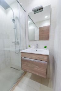 a bathroom with a sink and a shower with a mirror at Appartement Luxueux à Kouba in Kouba