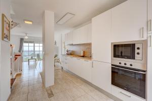カジャオ・サルバヘにある175 Tropical Views by Sunkeyrentsの白いキャビネットと大型オーブン付きのキッチンが備わります。