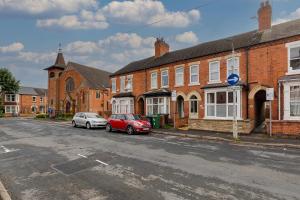 a street with two cars parked in front of brick buildings at Ground Floor Apartment with Courtyard in Loughborough