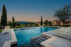 uma grande piscina com cadeiras e árvores e um edifício em Jacopo Farmhouse Apartment in Wine Resort in Lucca em Lucca