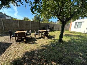 una mesa y sillas bajo un árbol en un patio en North London A spacious 7 bedroom house accommodating up to 18 people complete with own gym and table tennis en Londres