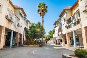 a street in a town with palm trees and buildings at relaxing duplex in ashdod by torohome in Ashdod