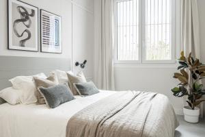biała sypialnia z dużym białym łóżkiem z poduszkami w obiekcie Apartamentos Pamplona by Clabao w Pampelunie