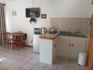 a kitchen with a sink and a refrigerator and a table at Apartment in Heather Park in George