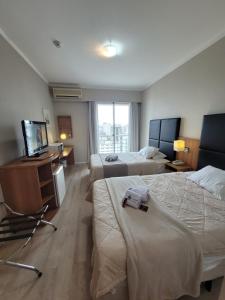 a hotel room with two beds and a television at Studio Living Slavieiro Moema in Sao Paulo