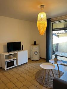 a living room with a couch and a tv and a table at Fos Plage - Studio in Fos-sur-Mer