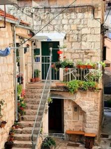 a stone building with stairs and a balcony with plants at Apartments and Rooms Petra in Split