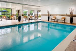 einen Pool in einer Hotellobby mit Stühlen und Tischen in der Unterkunft Courtyard by Marriott Charlotte Ballantyne in Charlotte