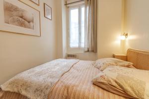 a bed in a bedroom with a window and a bedspread at Appartement cosy au cœur de la ville, au calme avec Wifi et linge de maison inclus in Cauterets