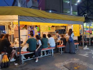 un gruppo di persone seduti in un chiosco di cibo di Seomun market Dongsan Hospital Cheongla Hill a Daegu