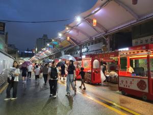 eine Gruppe von Menschen, die mit Sonnenschirmen die Straße hinuntergehen in der Unterkunft Seomun market Dongsan Hospital Cheongla Hill in Daegu