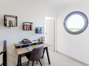 ein Büro mit einem Holzschreibtisch und einem runden Fenster in der Unterkunft Holiday Home Pirou Beach by Interhome in Pirou
