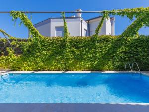 a swimming pool in front of a green hedge at Apartment Gabi - MDN151 by Interhome in Ližnjan