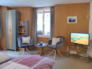 a bedroom with a bed and two chairs and a television at Apartment Rösli by Interhome in Stechelberg