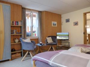 シュテッヘルベルクにあるApartment Rösli by Interhomeのベッドルーム1室(ベッド1台、椅子2脚、テレビ付)