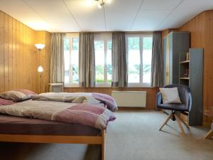 a bedroom with two beds and a chair and windows at Apartment Rösli by Interhome in Stechelberg