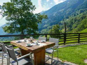 een houten tafel en stoelen met uitzicht op de bergen bij Holiday Home Rustico Girasole by Interhome in Leontica