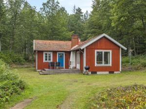 una pequeña casa roja con porche y patio en Chalet Ängsjömåla by Interhome en Eringsboda