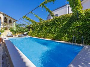 a swimming pool with a green hedge next to a building at Apartment Gabi - MDN152 by Interhome in Ližnjan