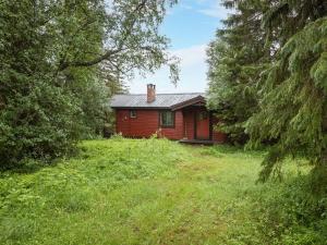 a red house in the middle of a field with trees at Chalet Högvallen Elden - JAM025 by Interhome in Undersåker