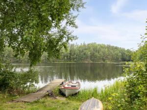 a small boat parked next to a dock on a lake at Holiday Home Klinten Totebo - SND150 by Interhome in Totebo