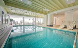 a large swimming pool with chairs in a building at Heart Hotel Aurora in Obertauern