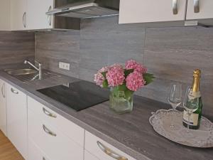 - une table avec un vase de fleurs roses et une bouteille de vin dans l'établissement Apartment Walzthöni by Interhome, à Wenns