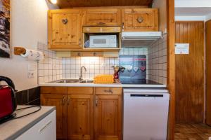 La cuisine est équipée de placards en bois et d'une cuisinière blanche. dans l'établissement Le Névé, à Crest-Voland