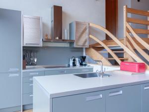 een witte keuken met een wastafel en een trap bij Chalet Mimique by Interhome in Nendaz
