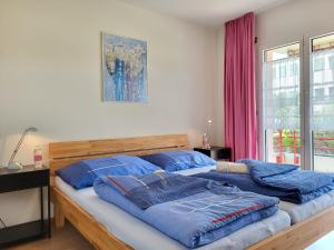 a bedroom with a bed with blue pillows on it at Apartment Caslago-1 by Interhome in Caslano