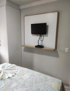 a bedroom with a tv on a wall with a bed at Village Taperapuan in Porto Seguro