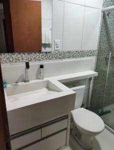 uma casa de banho com um lavatório, um WC e um espelho. em Village Taperapuan em Porto Seguro