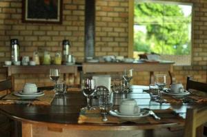 una mesa de madera con copas, platos y copas de vino en POUSADA PEQUIZEIRO en Chapada dos Guimarães