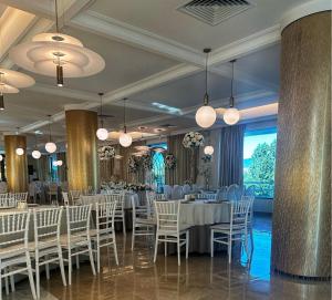un salón de banquetes con mesas y sillas blancas y ventanas grandes en Cruise Hotel, en Tiflis
