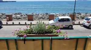 ein weißes Auto, das auf einem Parkplatz neben dem Meer parkt in der Unterkunft Hotel taromy in Neapel