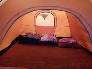 a tent with three pillows in it with a window at Glamping ReaVeeCafe Puncak in Puncak