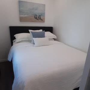 Elle comprend un grand lit blanc avec des oreillers blancs et un tableau. dans l'établissement Stunning Modern Container Home on Golden Lake, à Killaloe Station