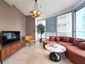 a living room with a couch and a tv at Gindi Tower Apartment - By Beach Apartments TLV in Tel Aviv