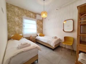 - une chambre avec 2 lits, un miroir et une chaise dans l'établissement Gindi Tower Apartment - By Beach Apartments TLV, à Tel Aviv