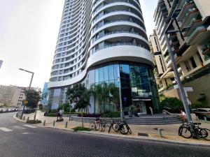 Gindi Tower Apartment - By Beach Apartments TLV في تل أبيب: مبنى طويل مع دراجات متوقفة أمامه