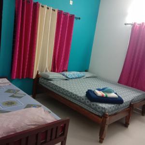 - une chambre avec 2 lits et des murs roses et bleus dans l'établissement Keralan Homestay, à Alappuzha