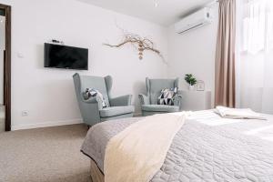 a bedroom with two chairs and a bed and a tv at Apartments by Pyramid: Christoph in Bratislava
