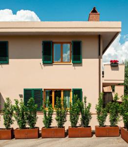 une maison avec des fenêtres vertes à volets et des plantes en pot dans l'établissement Cozy Apartment in the heart of Chianti (free Parking), à Pieve di Panzano