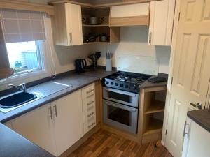 a small kitchen with a stove and a sink at K&Ds Caravans in Chapel Saint Leonards