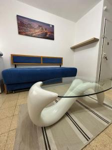 uma mesa de vidro com uma cadeira branca e um sofá azul em dgania lux em Qiryat H̱ayyim