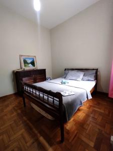 a bedroom with a large bed and a wooden floor at Apartamento completo no centro in Teresópolis